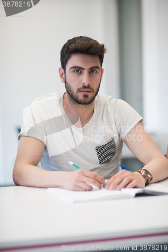 Image of male student taking notes in classroom