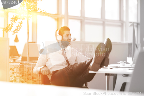 Image of relaxed young businessman first at workplace at early morning