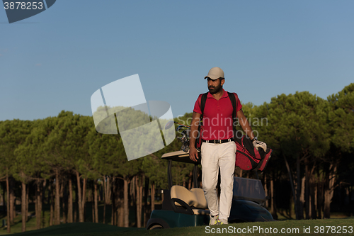 Image of golfer  walking and carrying golf  bag