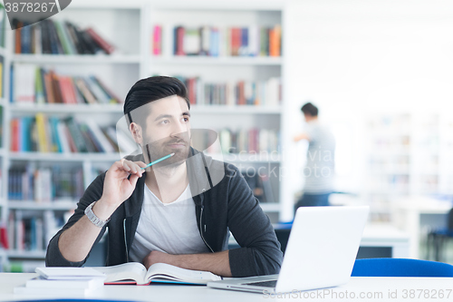 Image of student in school library using laptop for research