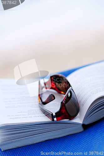 Image of Sunglasses and book on beach chair