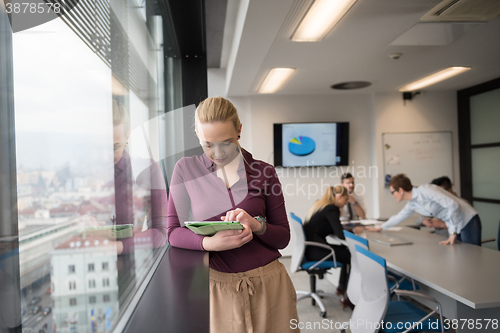 Image of blonde businesswoman working on tablet at office