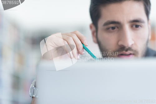 Image of student in school library using laptop for research