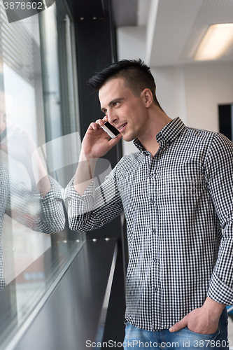 Image of young business man speaking on  smart phone at office