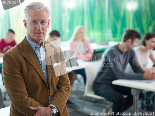 Image of portrait of in teacher in classroom with students group in backg