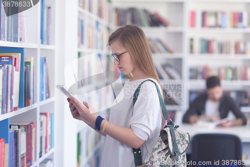 Image of famale student selecting book to read in library
