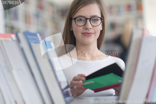 Image of portrait of famale student selecting book to read in library