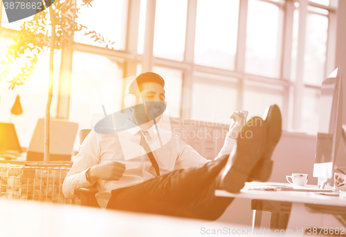 Image of relaxed young businessman first at workplace at early morning