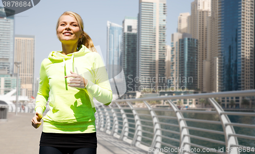 Image of happy young woman jogging outdoors