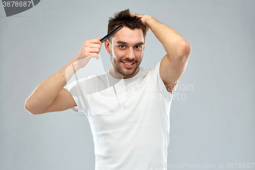 Image of happy man brushing hair with comb over gray