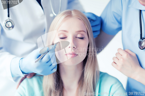 Image of plastic surgeon and nurse with patient