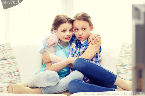 Image of scared little girls watching horror on tv at home