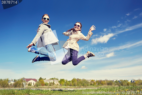 Image of happy little girls jumping high outdoors