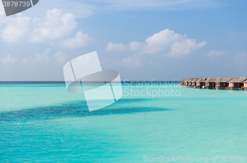 Image of bungalow huts in sea water on exotic resort beach