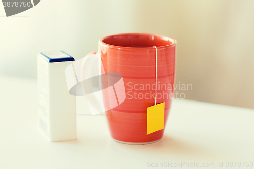 Image of close up of sweetener and tea cup on table