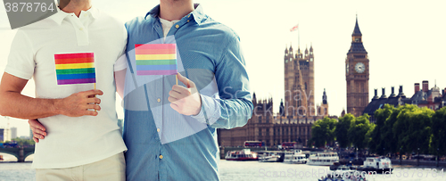 Image of close up of male gay couple with rainbow flags