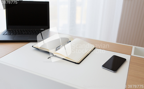 Image of notebook, laptop and smartphone on office table