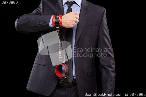 Image of man in a business suit with leather bound. handcuffs. sex Toys