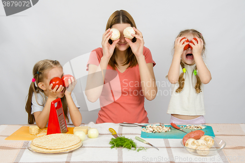 Image of Mum with two little girls having fun at the kitchen table playing with vegetables