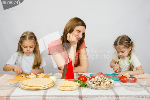 Image of Mother with tenderness looks like her little daughter to help her in the kitchen to prepare meals