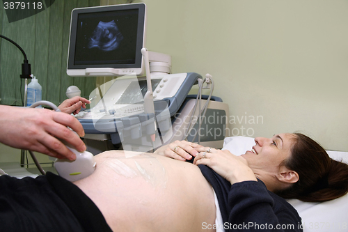 Image of Pregnant woman and doctor hand\'s with ultrasound equipment durin