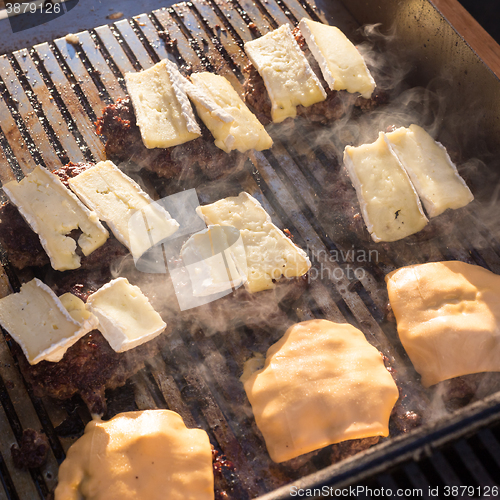 Image of Beef burgers being grilled on barbecue.