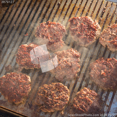 Image of Beef burgers being grilled on food stall grill.