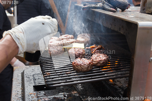 Image of Beef burgers being grilled on food stall grill.