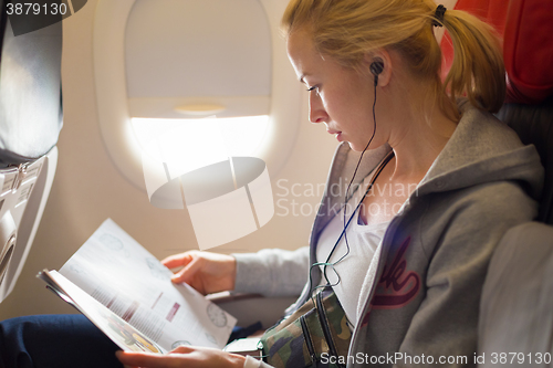 Image of Woman reading magazine on airplane.