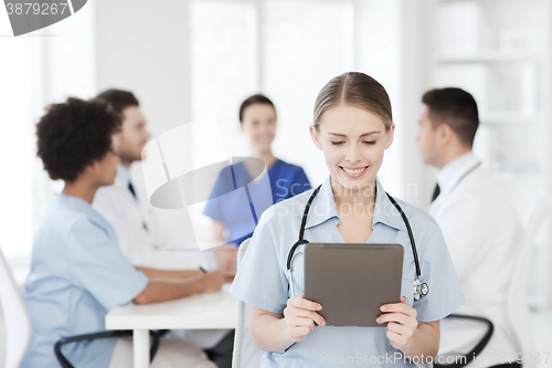 Image of happy doctor with tablet pc over team at clinic