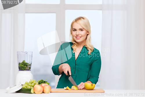 Image of smiling woman with blender cooking food at home