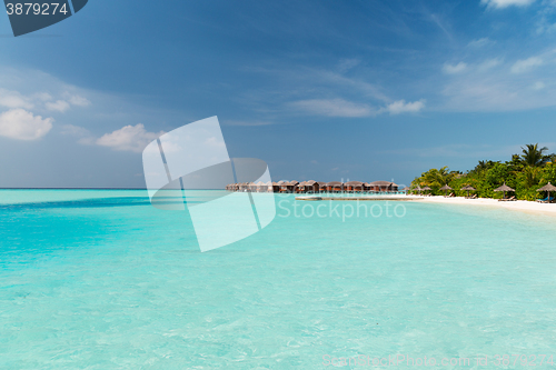 Image of bungalow huts in sea water on exotic resort beach