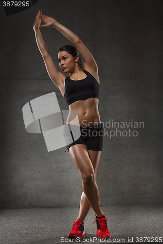 Image of young woman posing and showing muscles in gym
