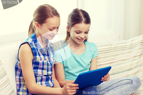 Image of happy girls with tablet pc sitting on sofa at home