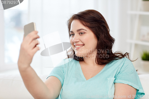 Image of happy plus size woman with smartphone at home