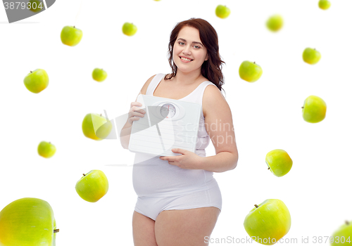 Image of happy young plus size woman holding scales