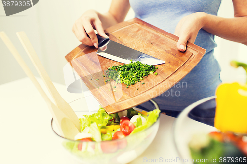 Image of close up of woman with chopped onion cooking salad