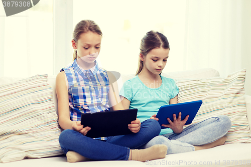 Image of girls with tablet pc sitting on sofa at home