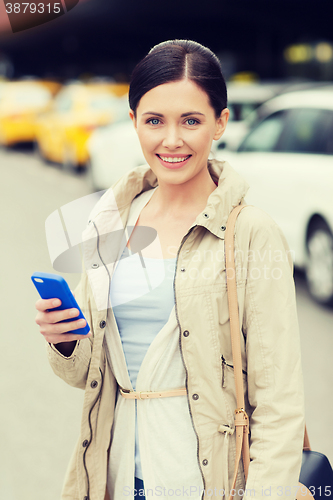 Image of smiling woman with smartphone over taxi in city