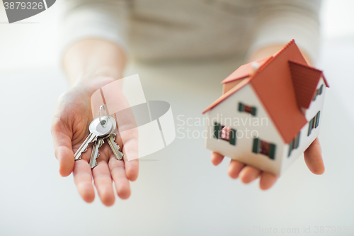 Image of close up of hands holding house model and keys