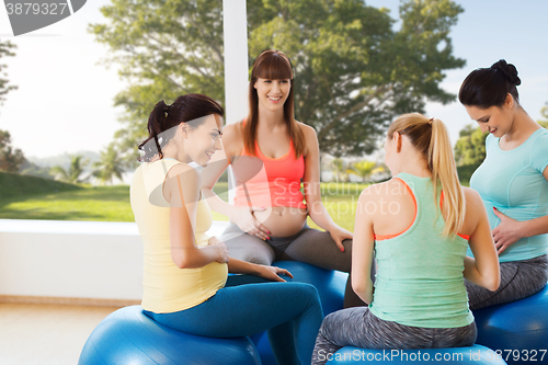 Image of happy pregnant women sitting on balls in gym