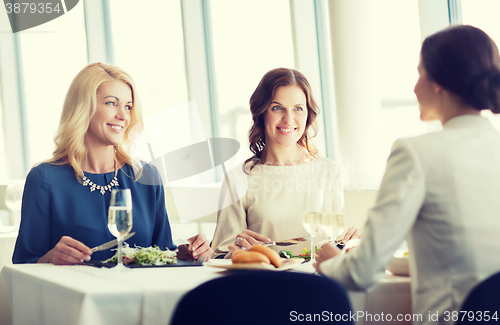 Image of happy women eating and talking at restaurant