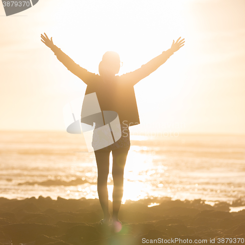 Image of Free woman enjoying freedom on beach at sunset.