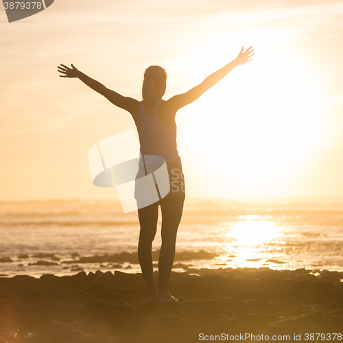 Image of Free woman enjoying freedom on beach at sunset.
