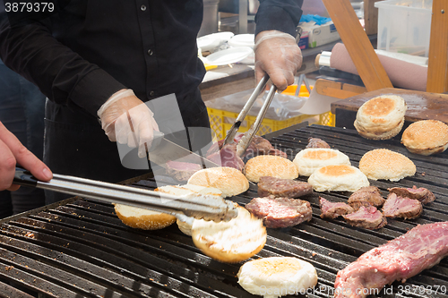 Image of Beef burgers being grilled on food stall grill.
