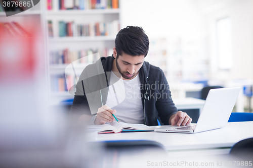 Image of student in school library using laptop for research