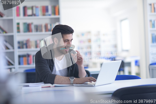 Image of student in school library using laptop for research