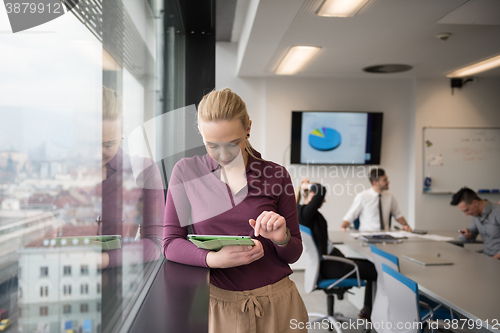 Image of blonde businesswoman working on tablet at office