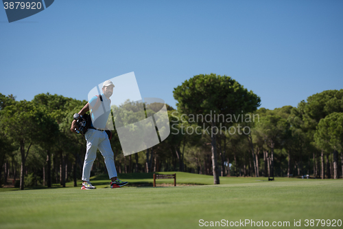 Image of golf player walking and carrying bag