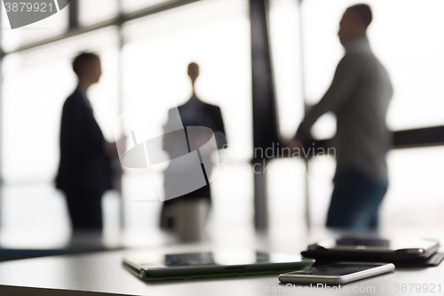 Image of close up of tablet, business people on meeting in background